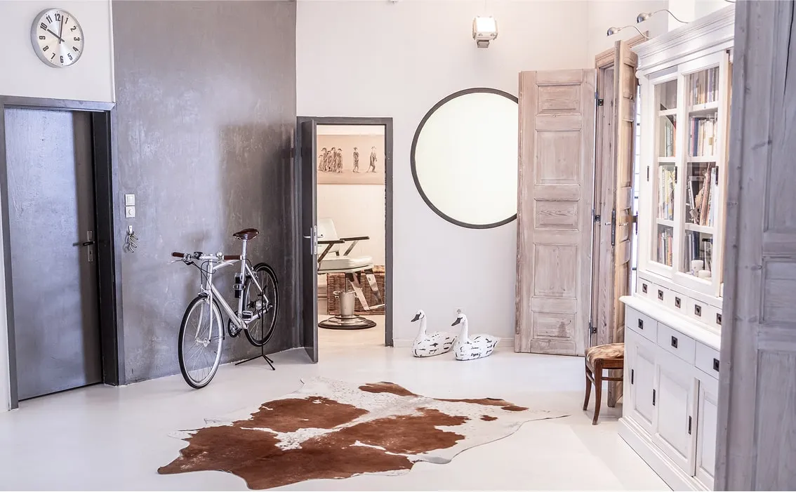 Eingangsbereich mit Fahrrad, Fellteppich und rundem Spiegel an der Wand – stilvolle Eventlocation Hamburg mit Hinterhof-Flair.