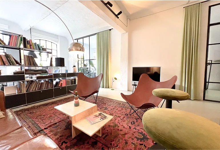 Gemütlicher Loungebereich mit Regal, Teppich und Sitzmöbeln – Loftstudio Hamburg als Eventlocation und Raum für Meetings.