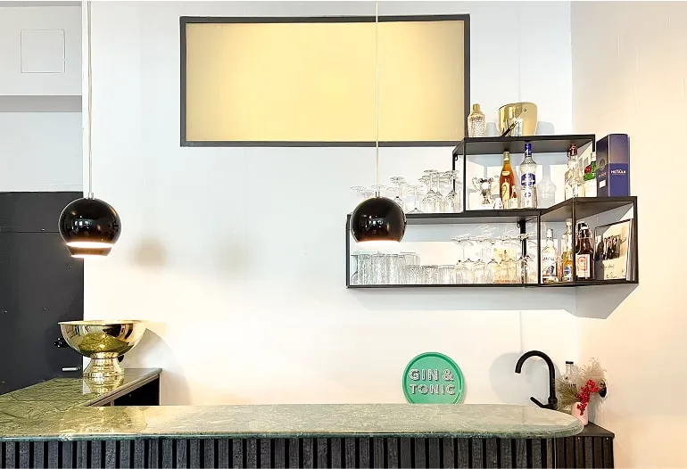 Stilvoller Wohnbereich mit Bar, Hockern und farbigen Akzenten.