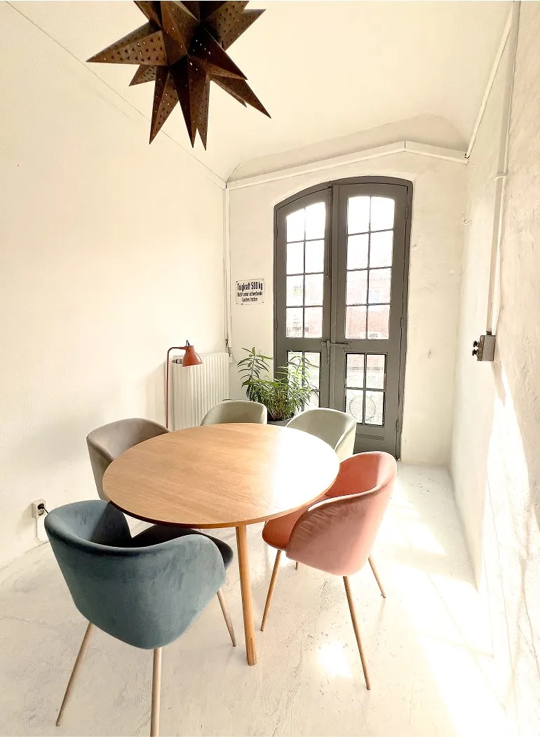 Lichtdurchfluteter Raum mit Glastür, Esstisch und Blick ins Grüne.