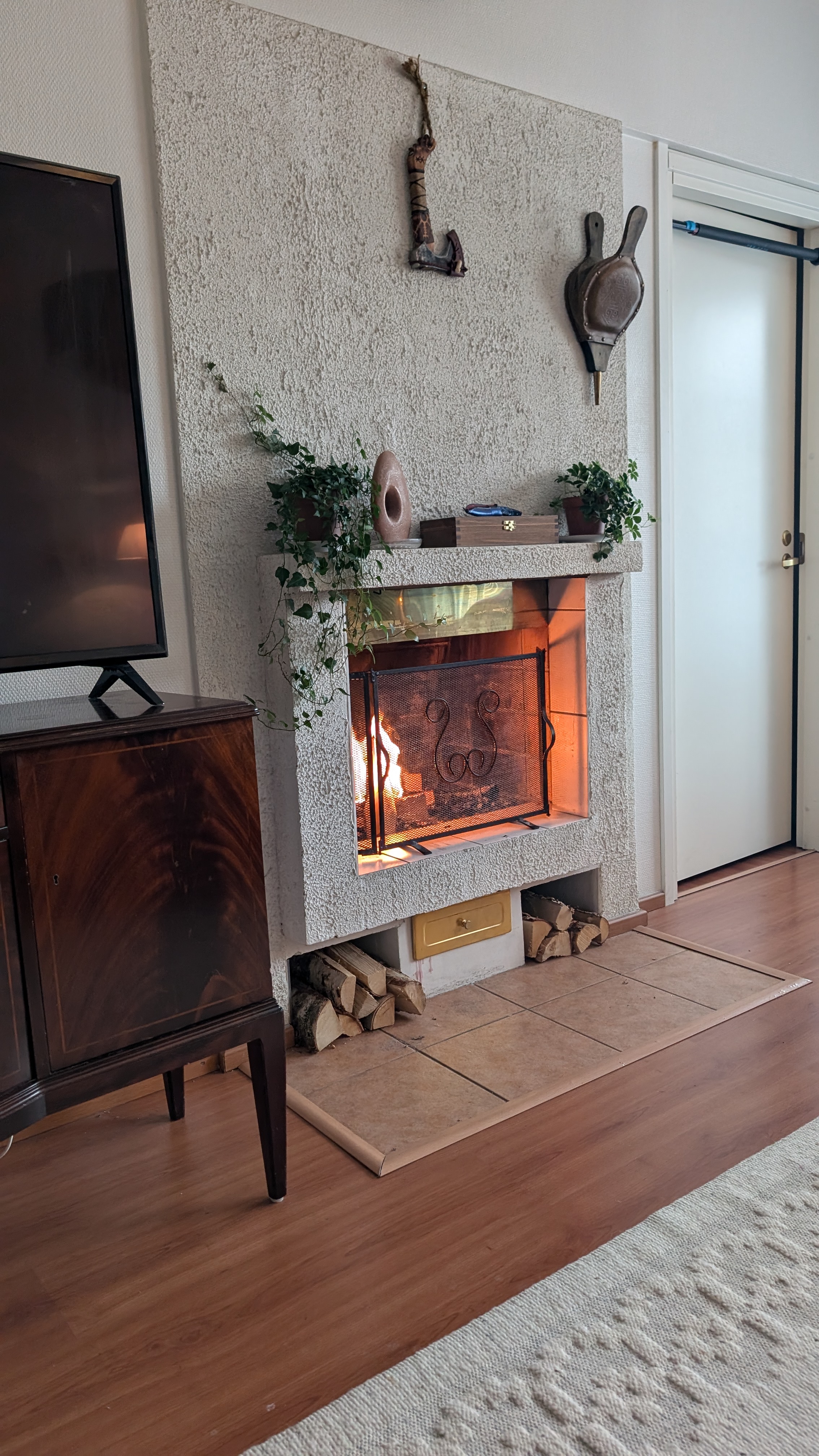 Fireplace with a Viking axe in front of a TV on a wooden cabinet in a cozy city apartment in Rovaniemi, Finland