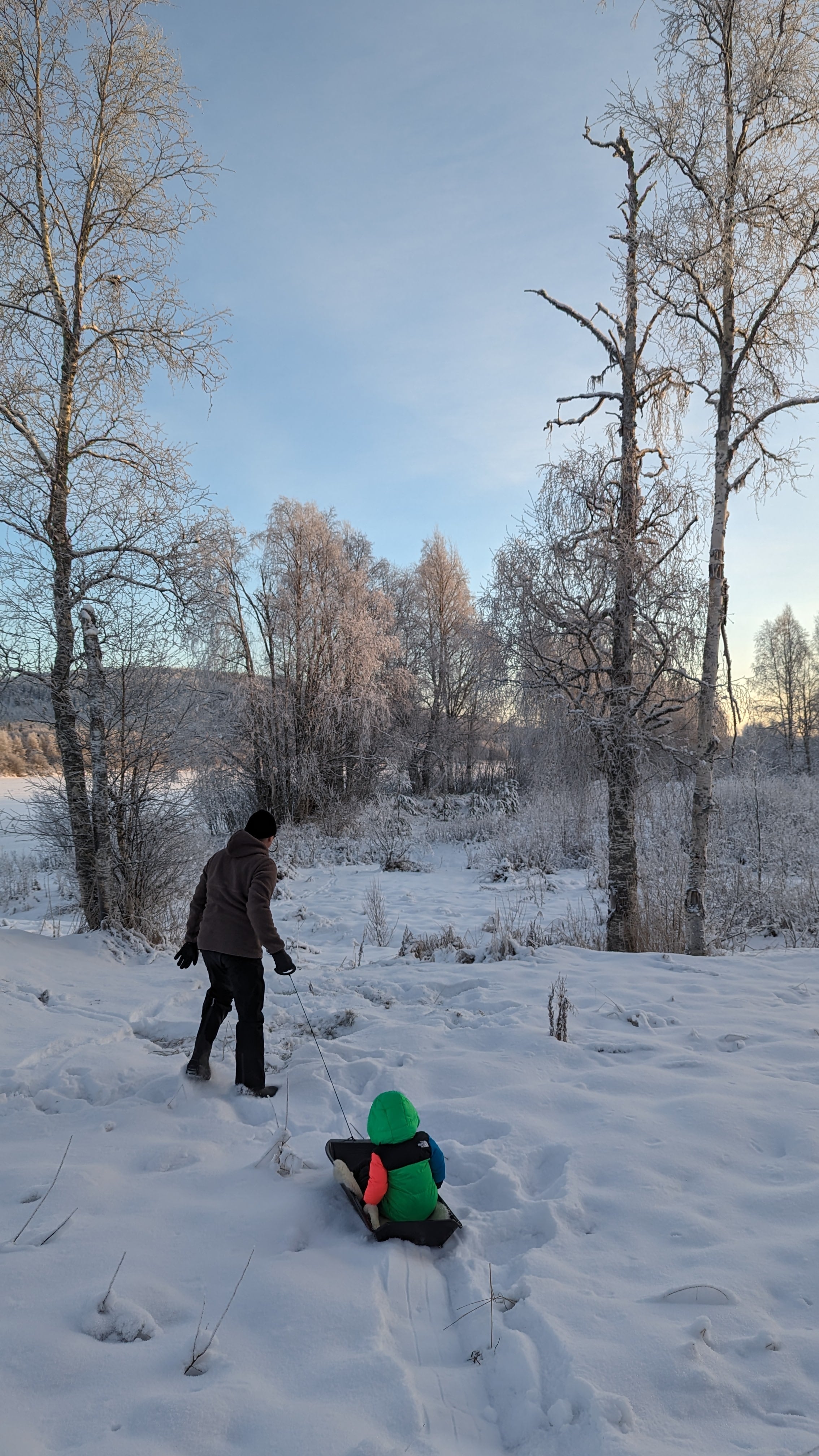 Little boy riding on a sleigh with his father in snowy Rovaniemi, Lapland.