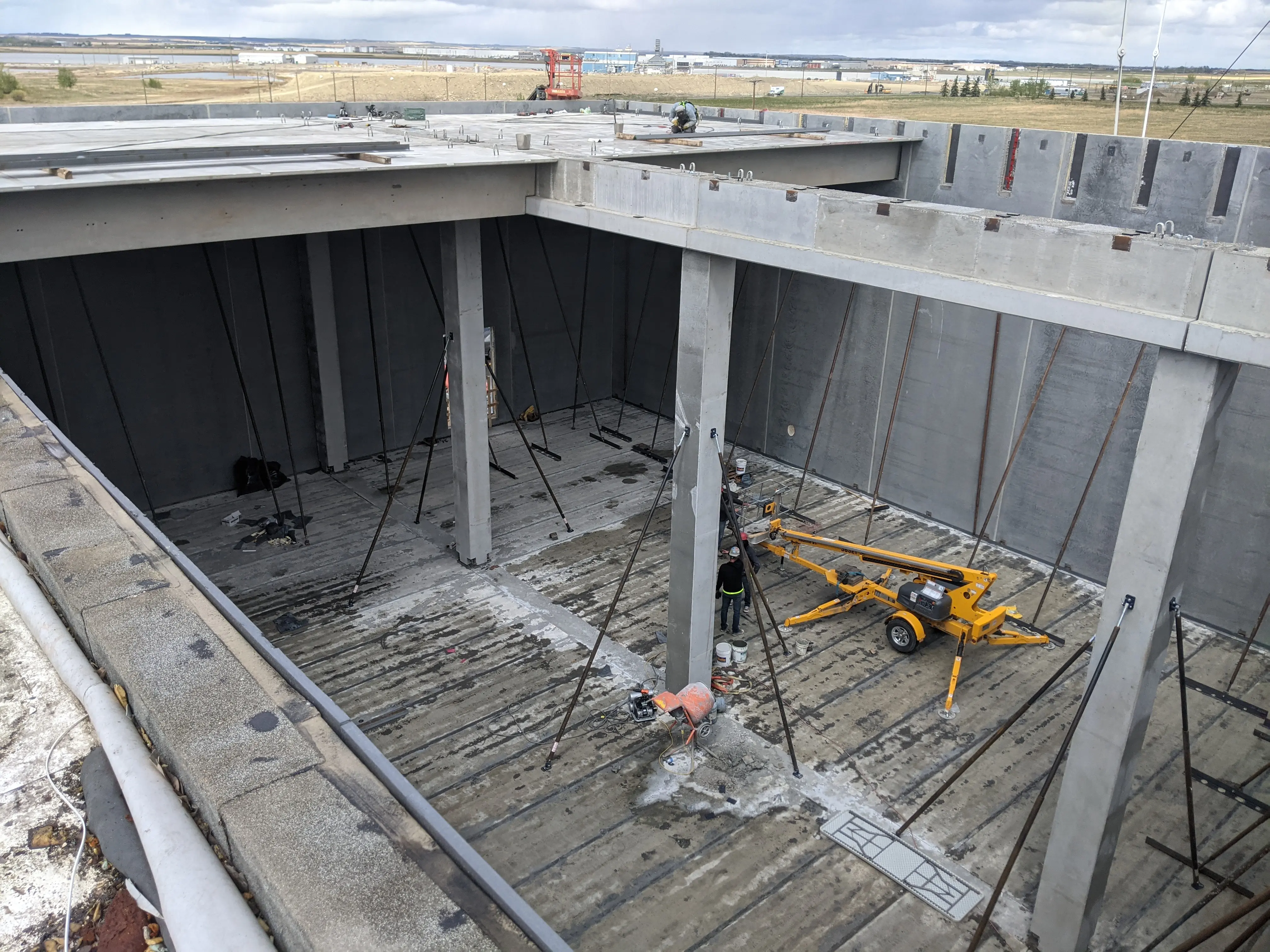 Interior of an industrial warehouse with a yellow overhead gantry crane labeled “25 Tonne” installed on steel beams, with a construction vehicle parked below.