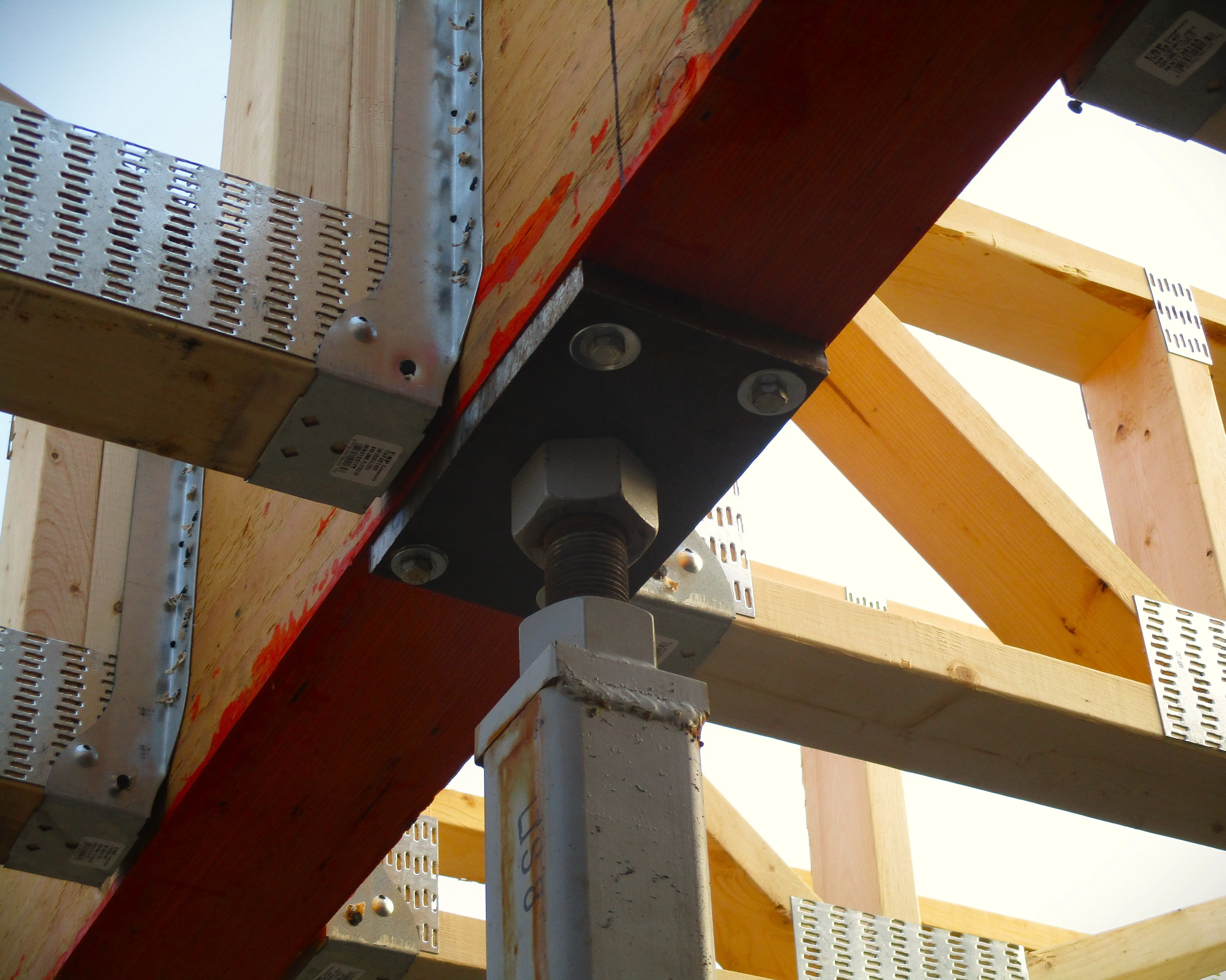 Close-up view of structural steel and timber connections, showing bolted joints and metal brackets securing wooden beams.