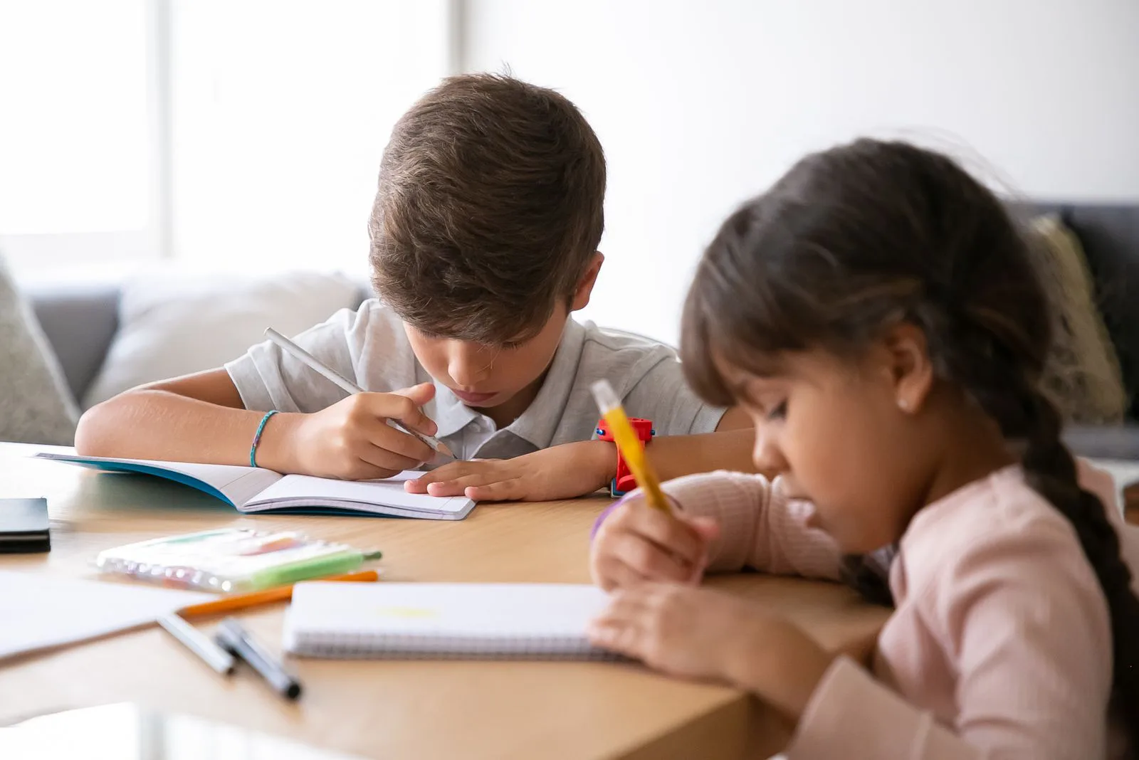 Two school-age children doing homework together at a table