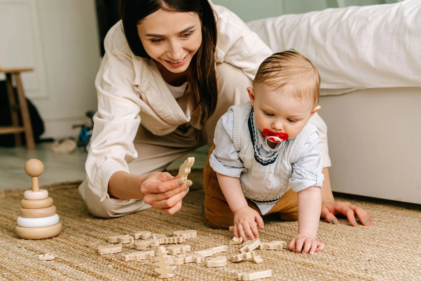 A mother and toddler playing with wooden toys on the floor