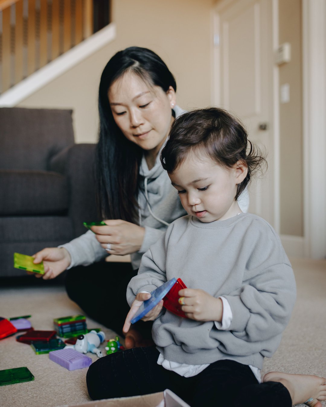 A mother and her child playing with toys together on the living room floor
