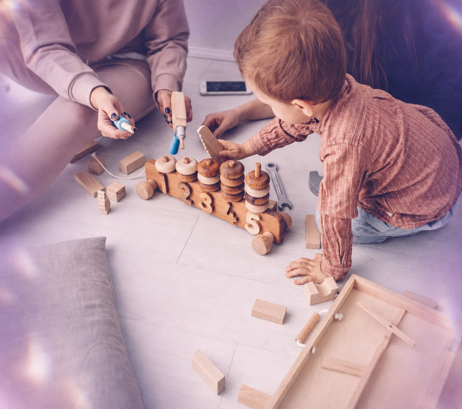 A parent waving during a virtual ABA session while her toddler plays beside her