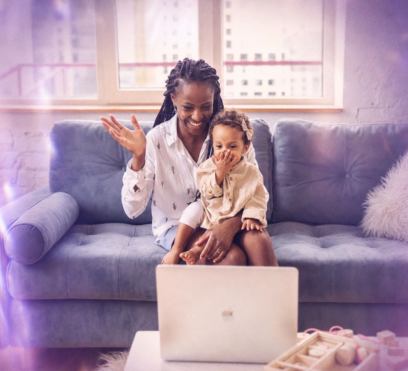 A parent and toddler waving during a video call at home