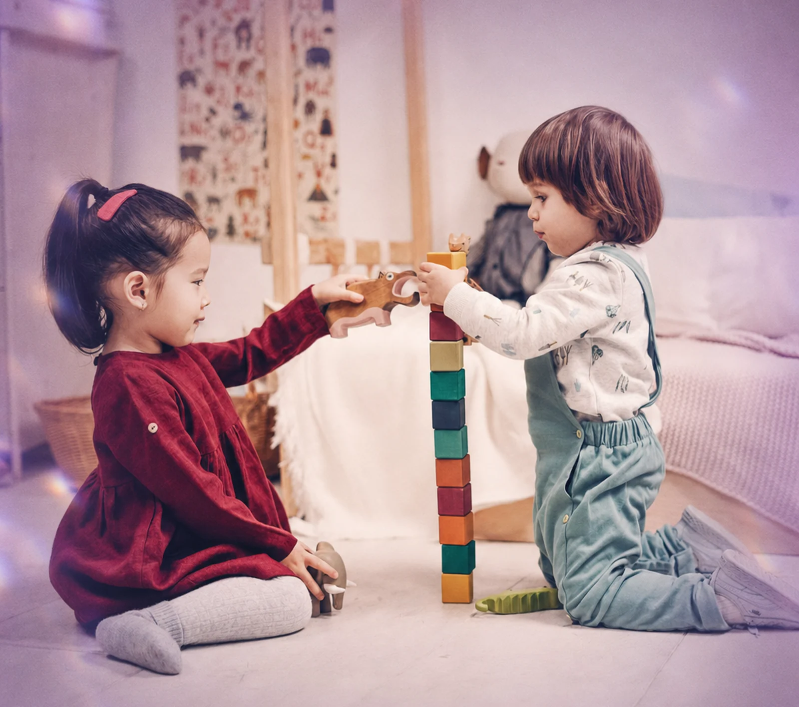 A parent waving during a virtual ABA session while her toddler plays beside her
