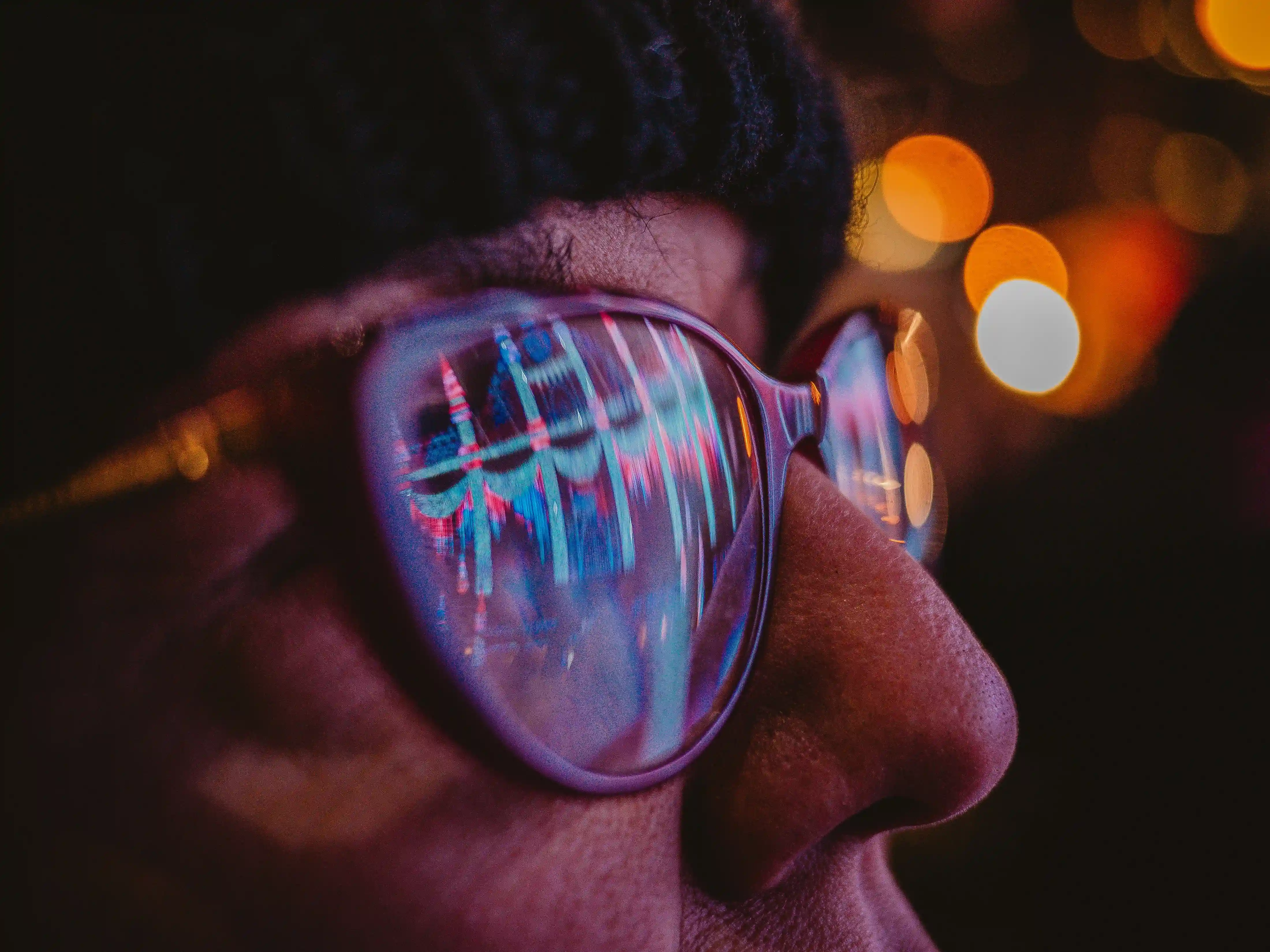 Close-up of a person wearing eyeglasses with colourful digital reflections in the lenses, highlighting modern vision and screen use