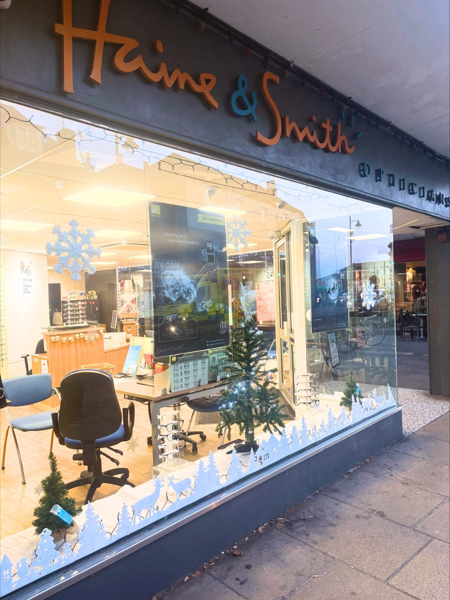 Haine & Smith Opticians storefront decorated with festive winter window displays, showcasing eyewear and eye care services