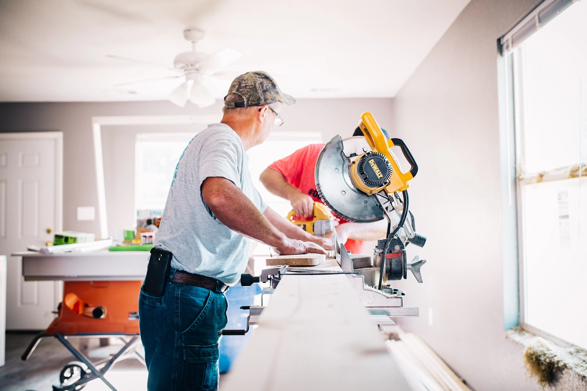 Two tradespeople using power tools and cutting materials during a home renovation project