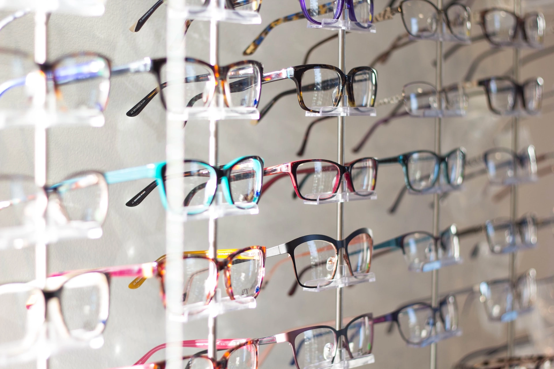 Wide selection of prescription eyeglass frames displayed on a wall-mounted eyewear rack inside an opticians practice