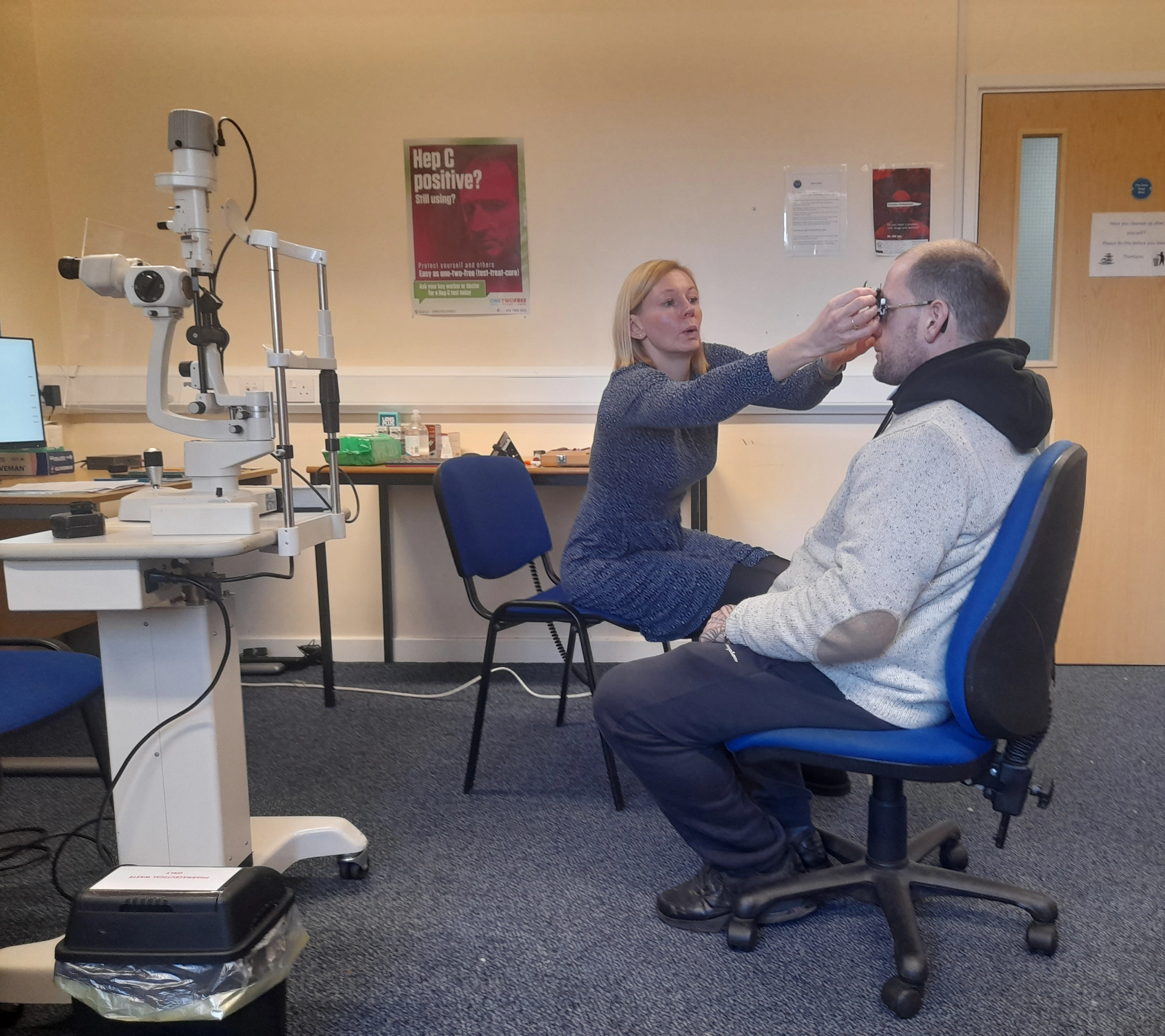 Eye care professional conducting an eye assessment and fitting procedure with a patient in a clinical examination room