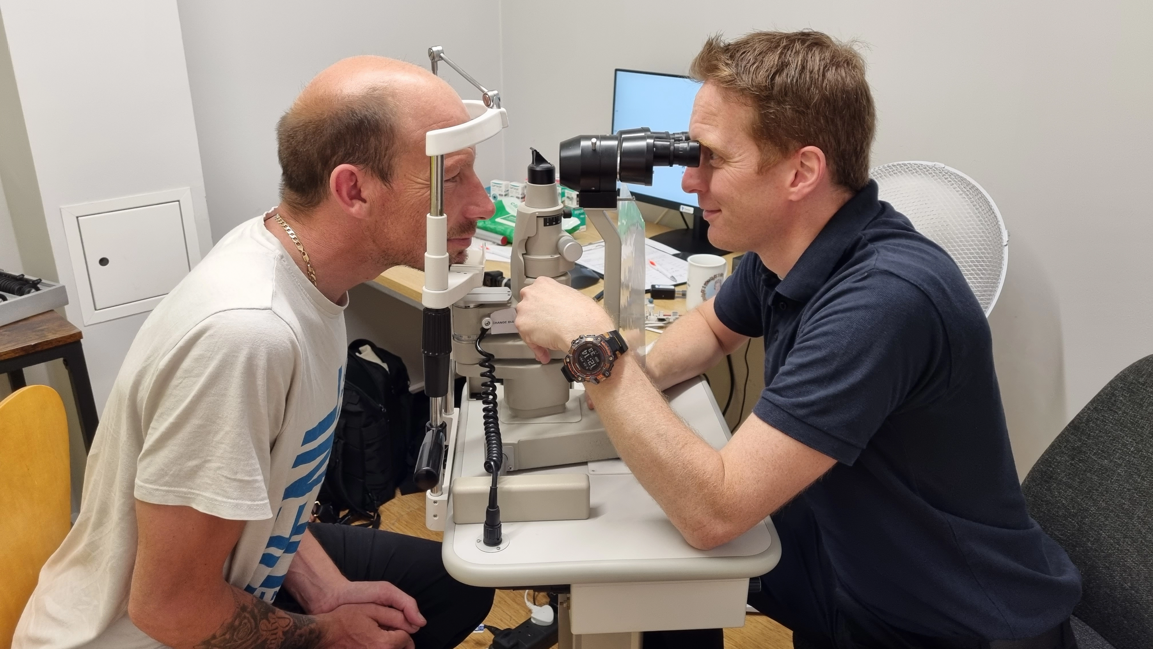 Optometrist performing a detailed eye examination on a patient using a slit lamp microscope in a clinical setting