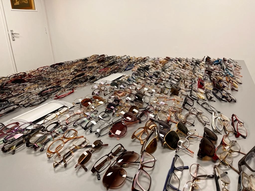 Large collection of donated eyeglasses and sunglasses arranged across tables, ready for sorting and reuse