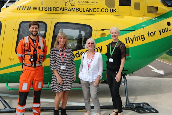Haine & Smith team with Wiltshire Air Ambulance crew member in front of the rescue helicopter