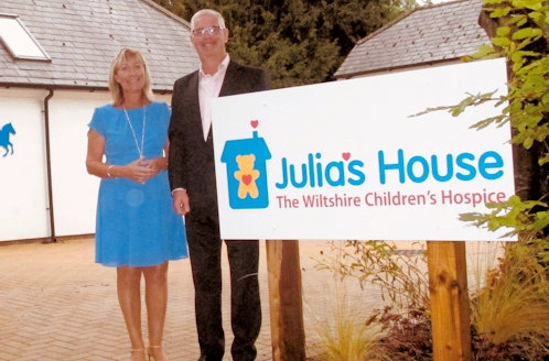 Haine & Smith representatives standing beside the Julia's House Wiltshire Children's Hospice sign