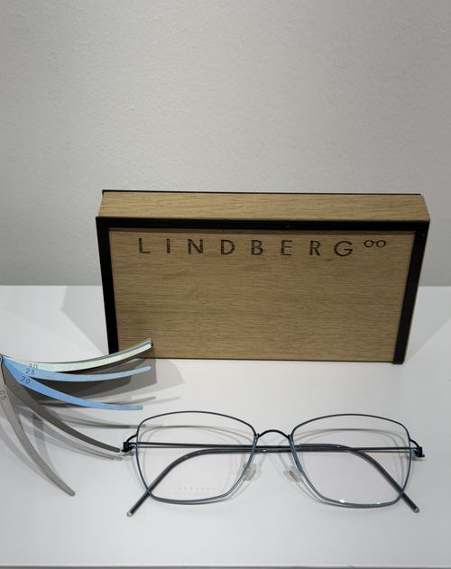 Lindberg eyeglass frames displayed alongside interchangeable temple arm samples and branded packaging