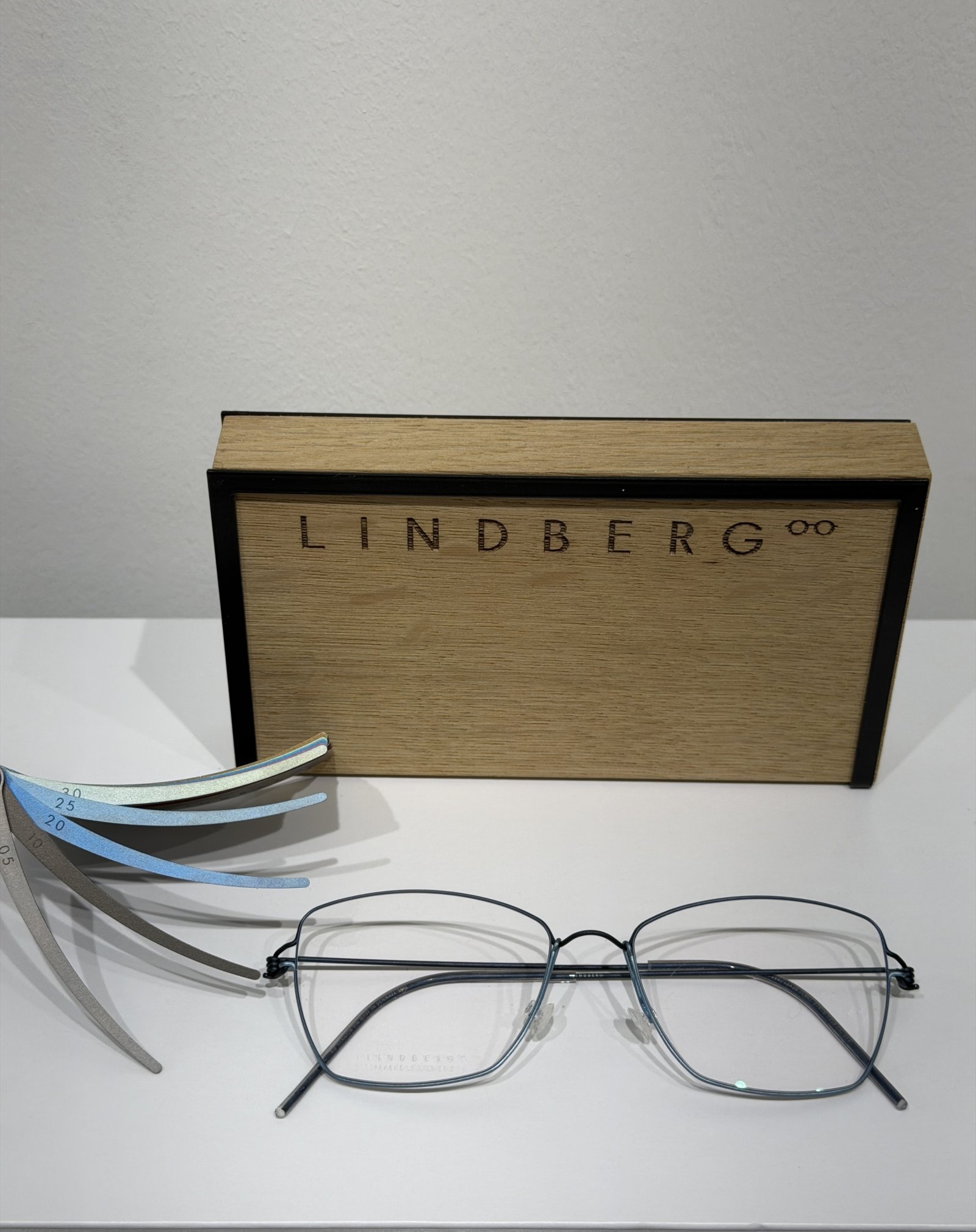 Lindberg eyeglass frames displayed alongside interchangeable temple arm samples and branded packaging