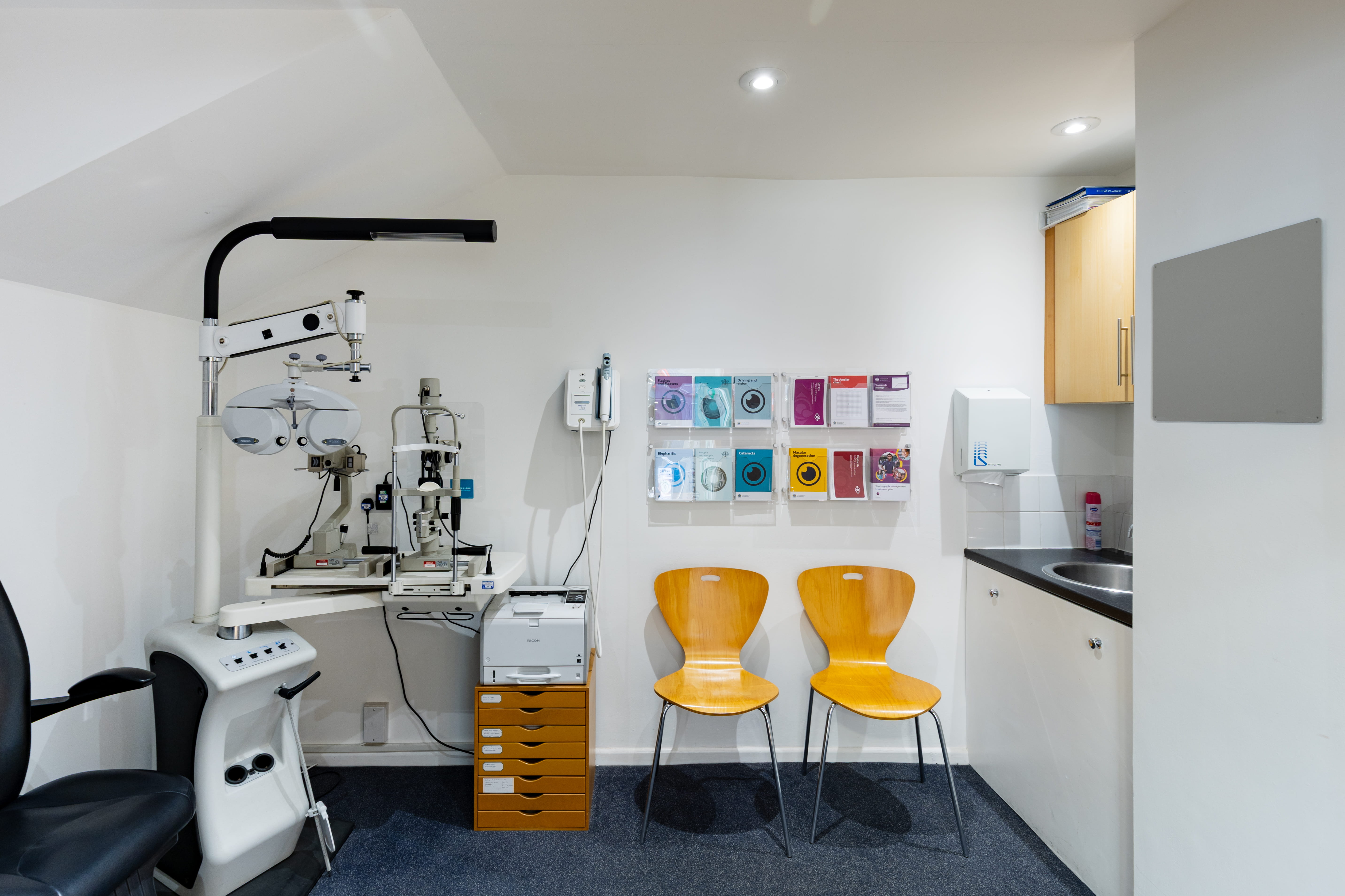 Modern eye examination room equipped with specialist optometry equipment, patient seating, and diagnostic instruments used for comprehensive eye health assessments and vision testing