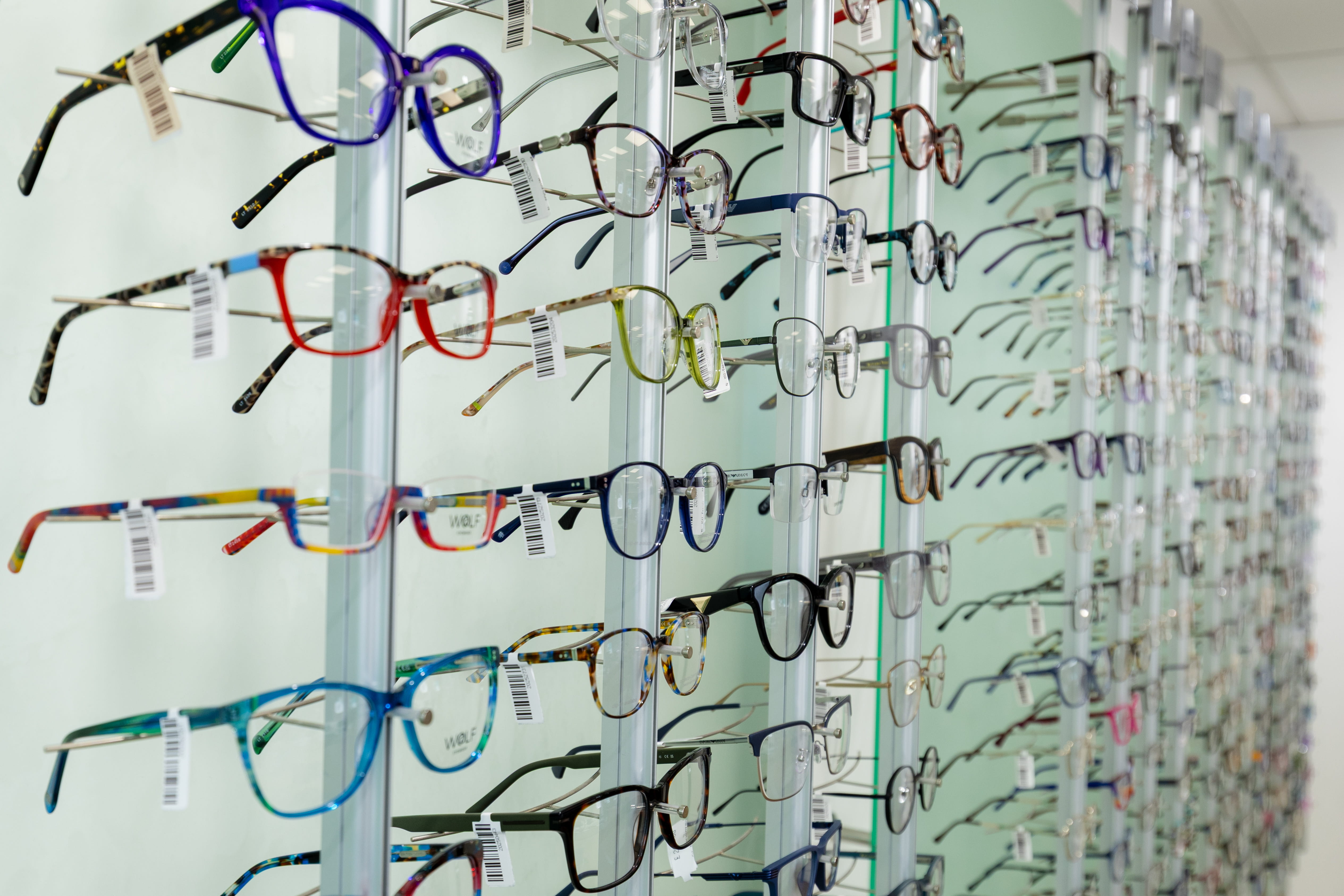 Display wall featuring a wide selection of colourful prescription glasses and designer eyewear frames inside a modern optician practice