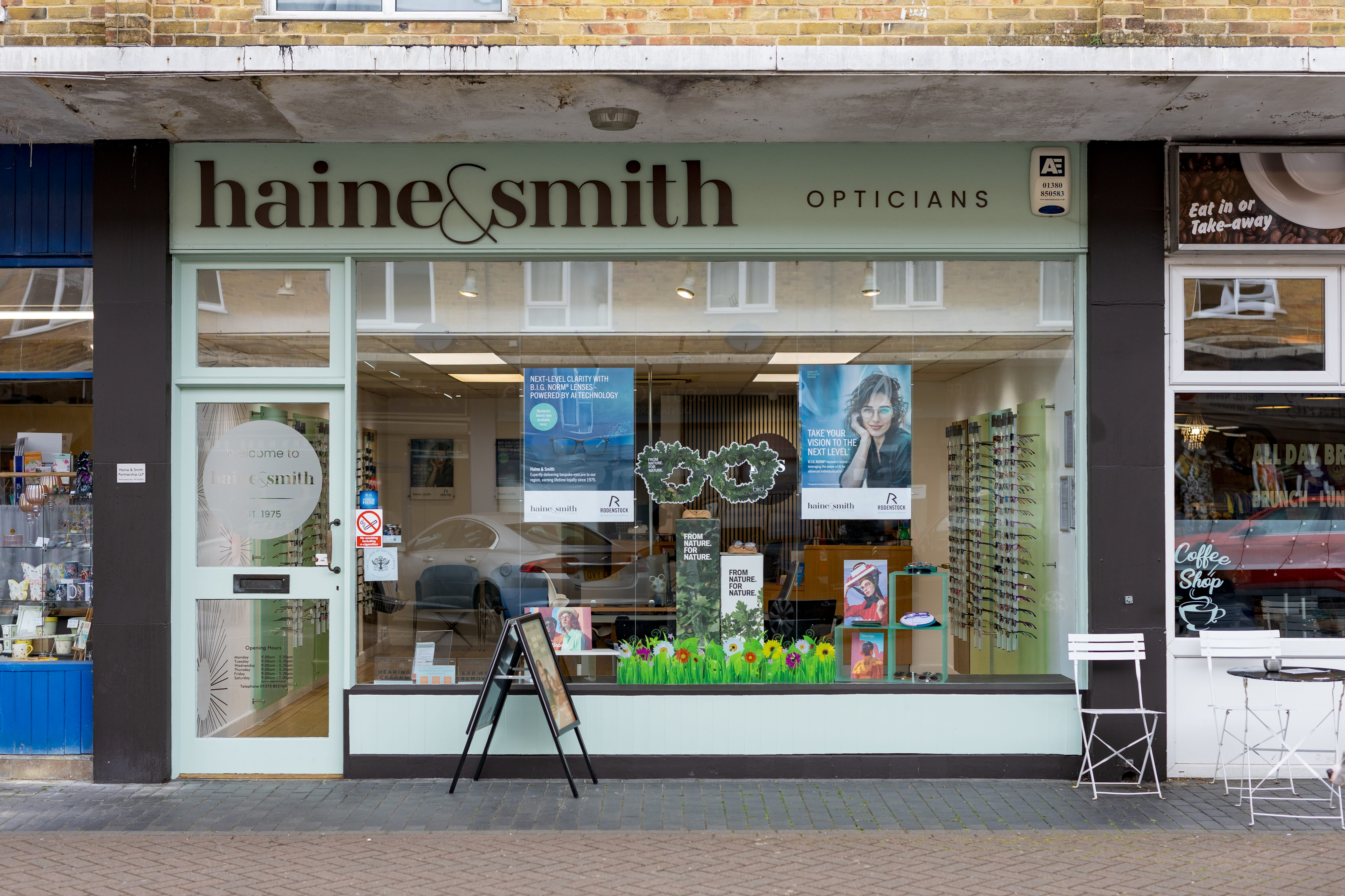 Front exterior of Haine & Smith Opticians showing a modern optical practice with large display windows, eyewear collections, promotional eye care posters, and a welcoming high street storefront