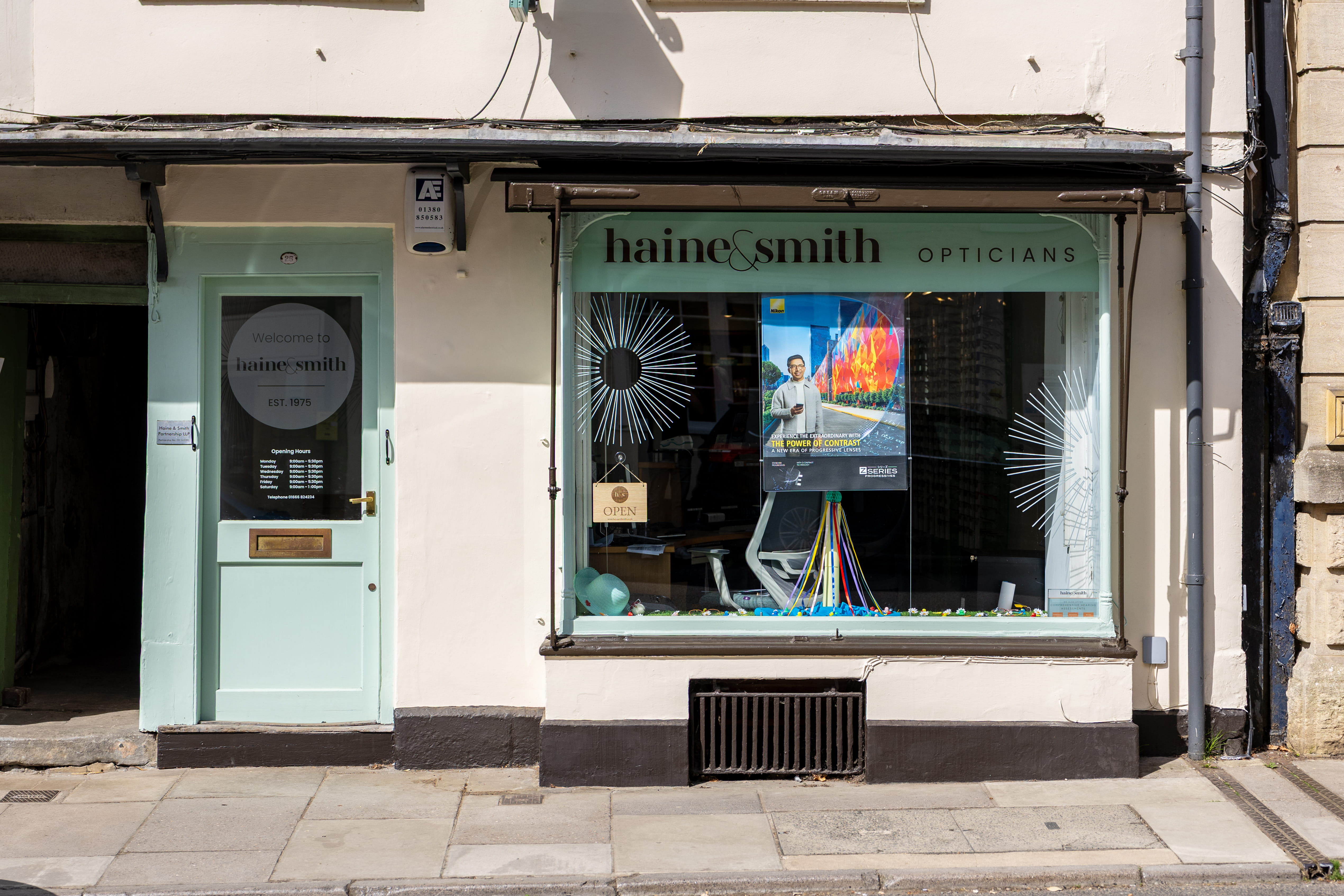 Exterior of a Haine & Smith Opticians practice featuring branded signage, a welcoming entrance, and a large display window showcasing eyewear promotions in a traditional town centre location