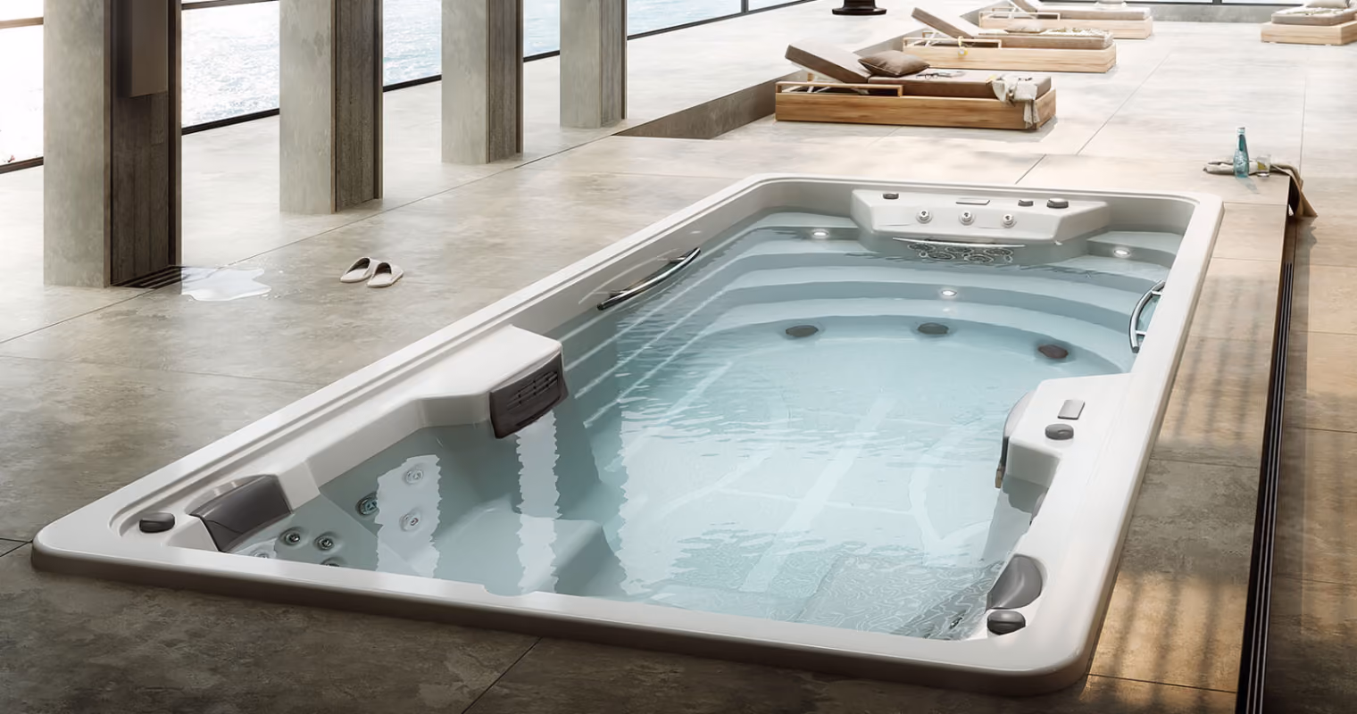 Moderne binnenzwembad met jacuzzi-functie en ligstoelen rondom met uitzicht op water buiten.