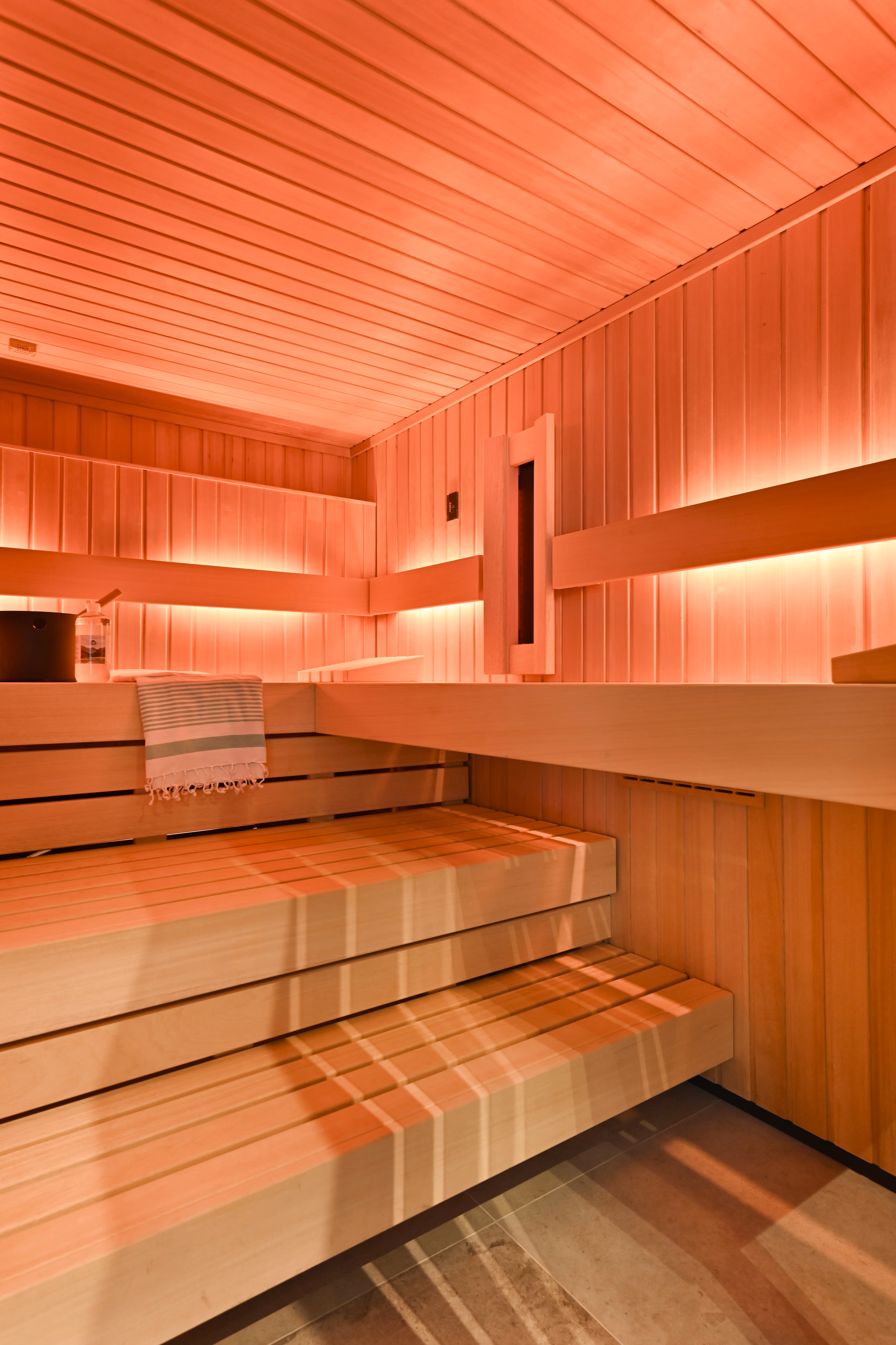 Moderne sauna met houten banken en warme sfeerverlichting langs de wanden.