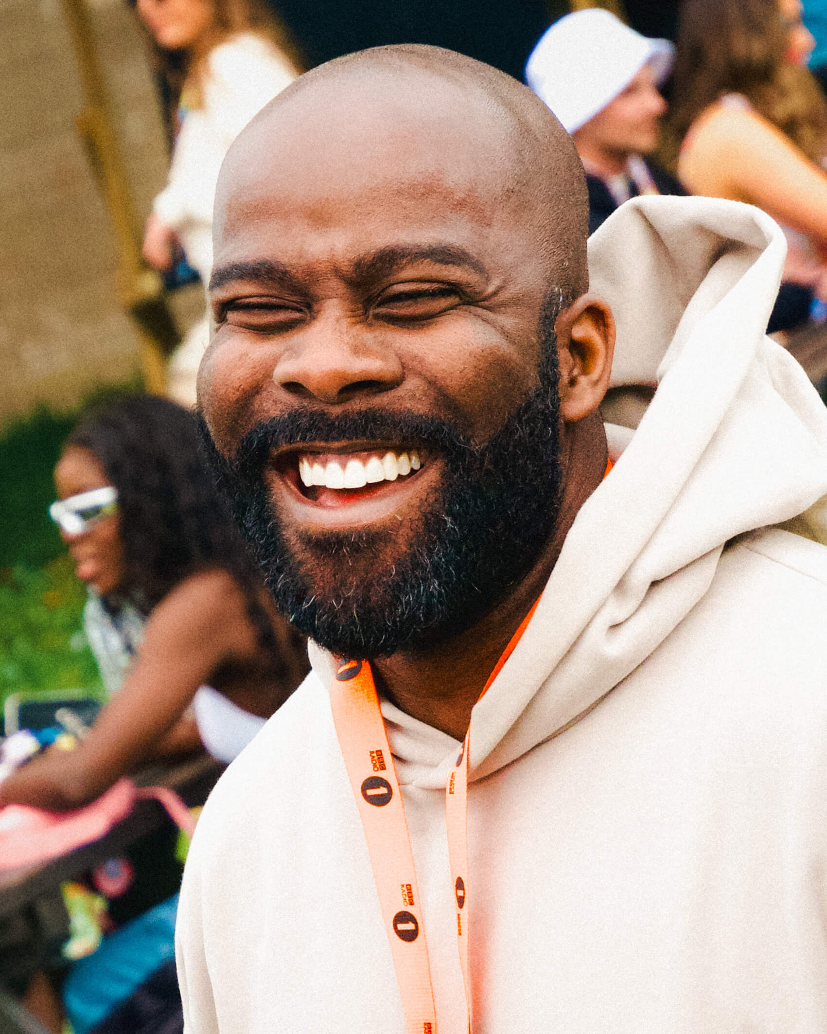 Radio host Melvin Odoom smiling off camera at Radio 1's big weekend wearing an orange lanyard
