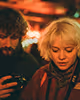 A man and woman stand side by side in a dimly lit room, conveying a sense of collaboration and focus.