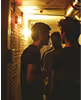 Three men stand in a hallway, engaged in conversation about free access to shows and listening parties in various cities.