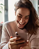 A woman happily using her phone, representing genuine engagement and the power of real content creation.