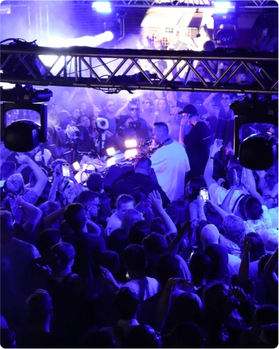 A lively crowd of people dancing at a nightclub illuminated by vibrant blue lights.