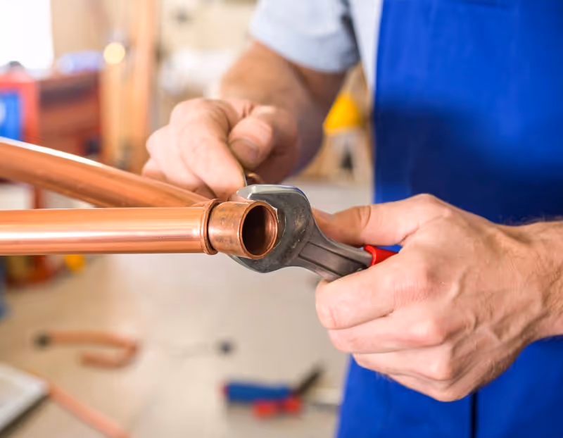Plumber's hands working on broken copper pipe in Winter Garden area