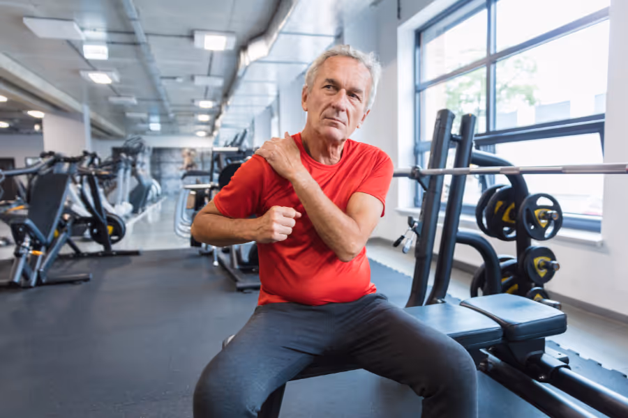 older man doing rehab after shoulder arthroscopy in the gym