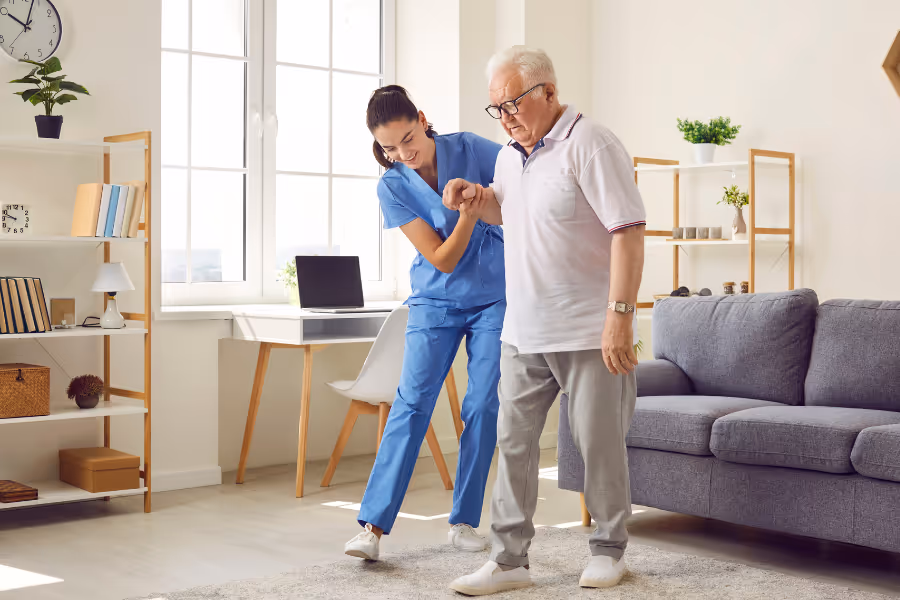 older ma being helped walking by a medical professional