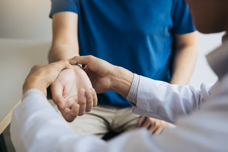 surgeon diagnosing man's wrist pain