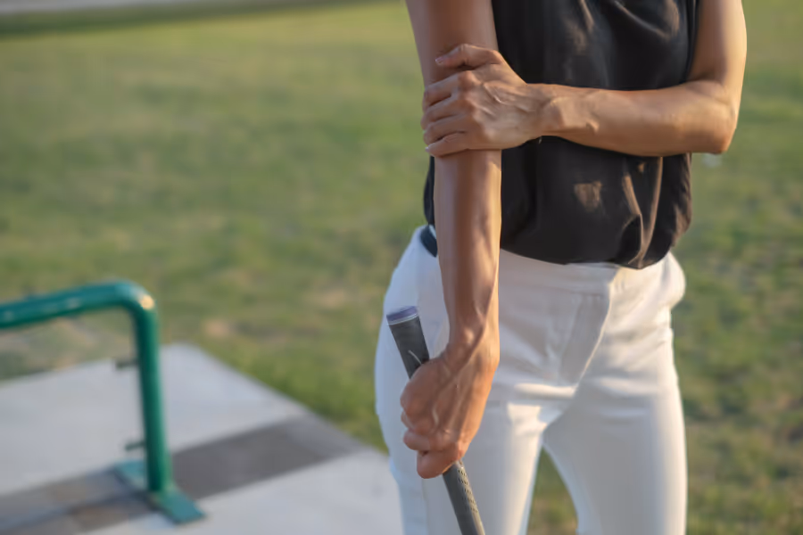 golfer holding her elbow in pain