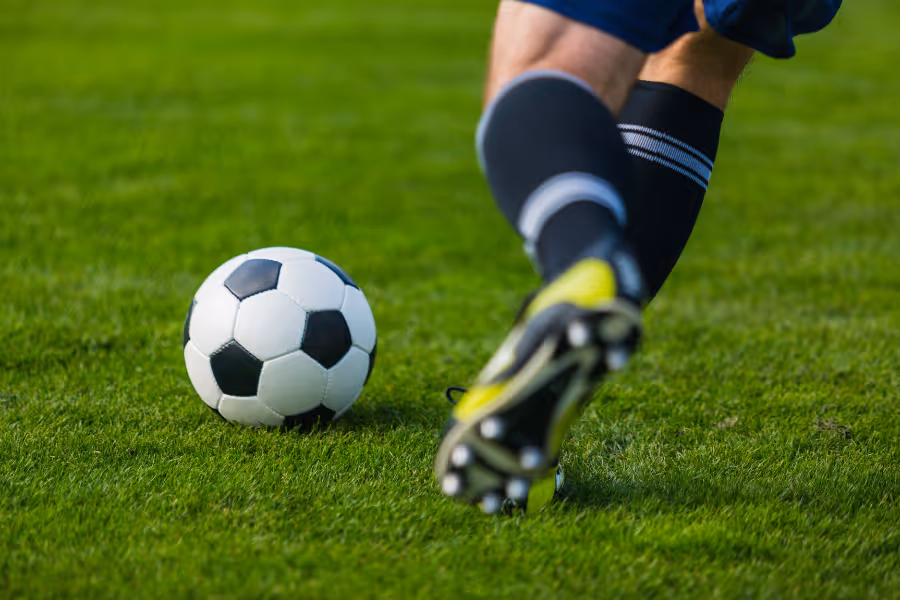 Soccer player about to kick the ball on a green field