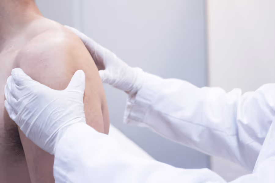Surgeon inspecting patients naked shoulder