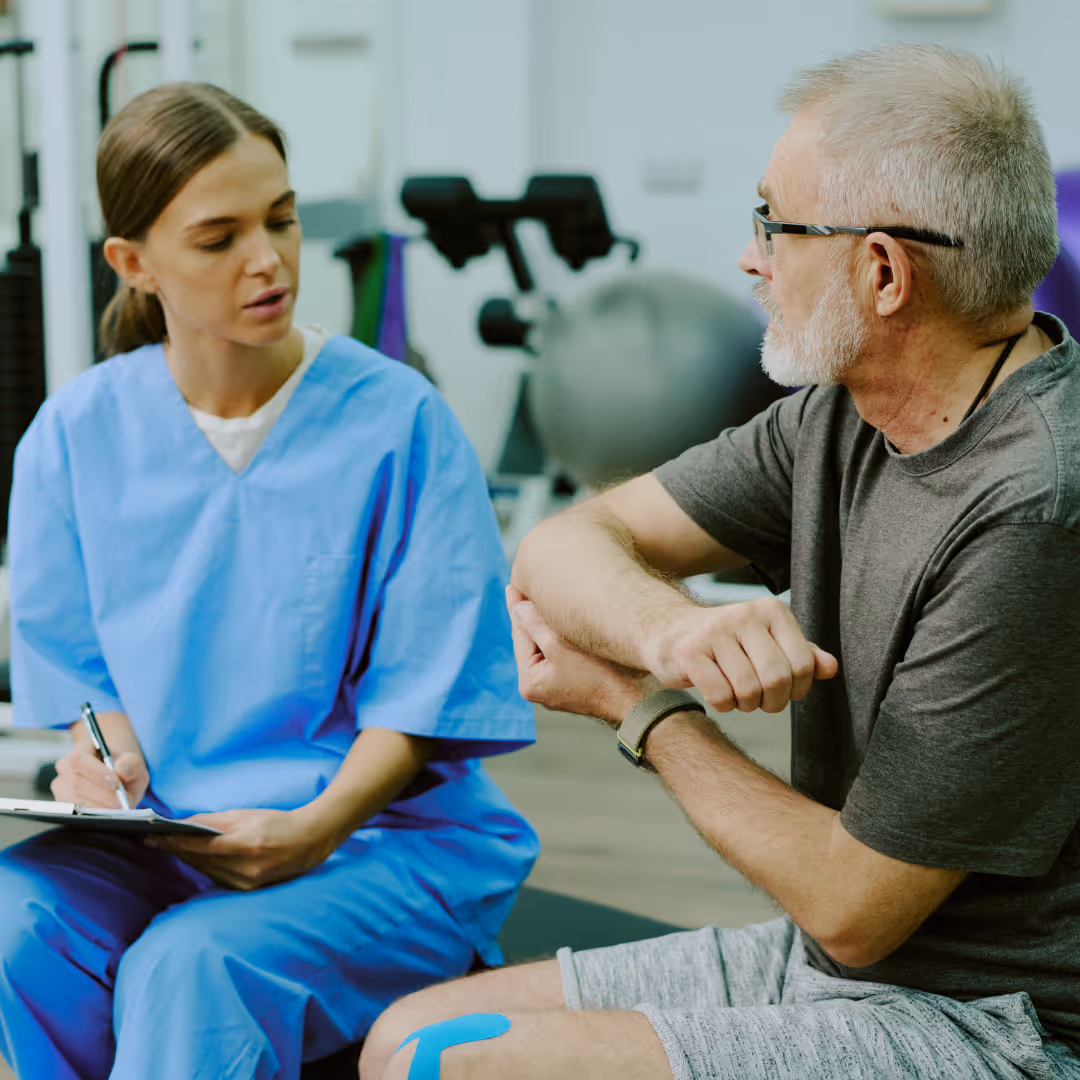 Man showing female physio his elbow in gym