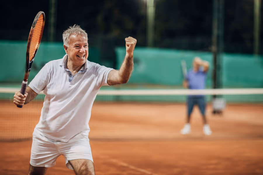 Older man grinning victoriously on the tennis court