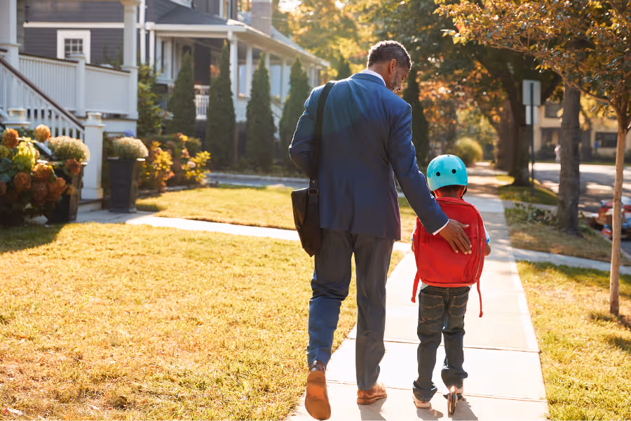 Man walking his son to school in suburban street