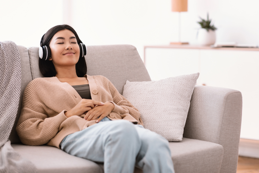 Young woman on a couch listening to music ear-pain free