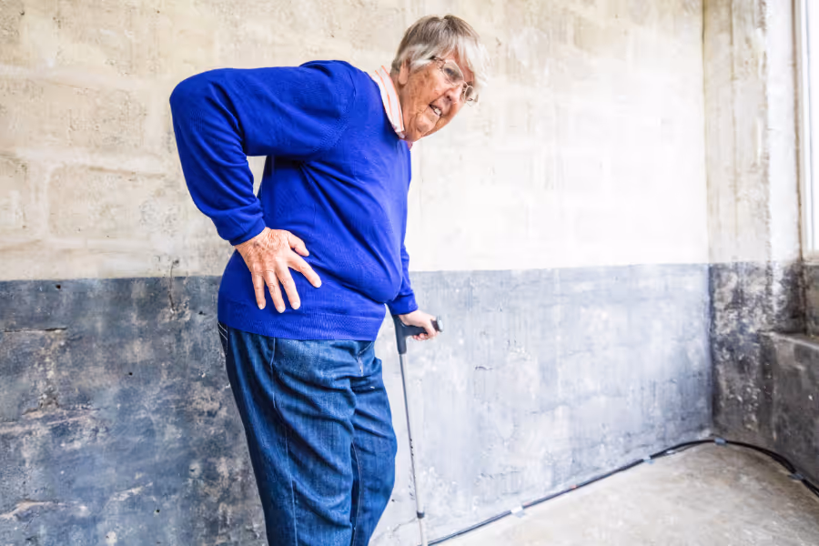 Older woman in visible hip pain using a crutch