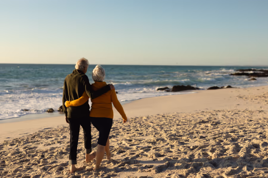 Older couple walking on picturesque beach, unencumbered by hip surgery pain