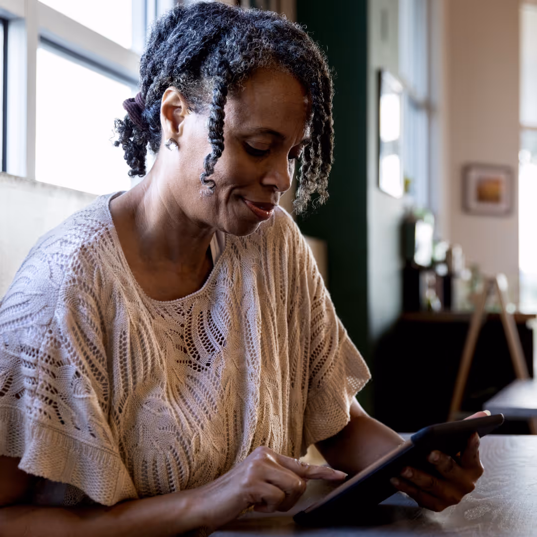 Woman in a cafe researching urinary incontinence procedures on an ipad